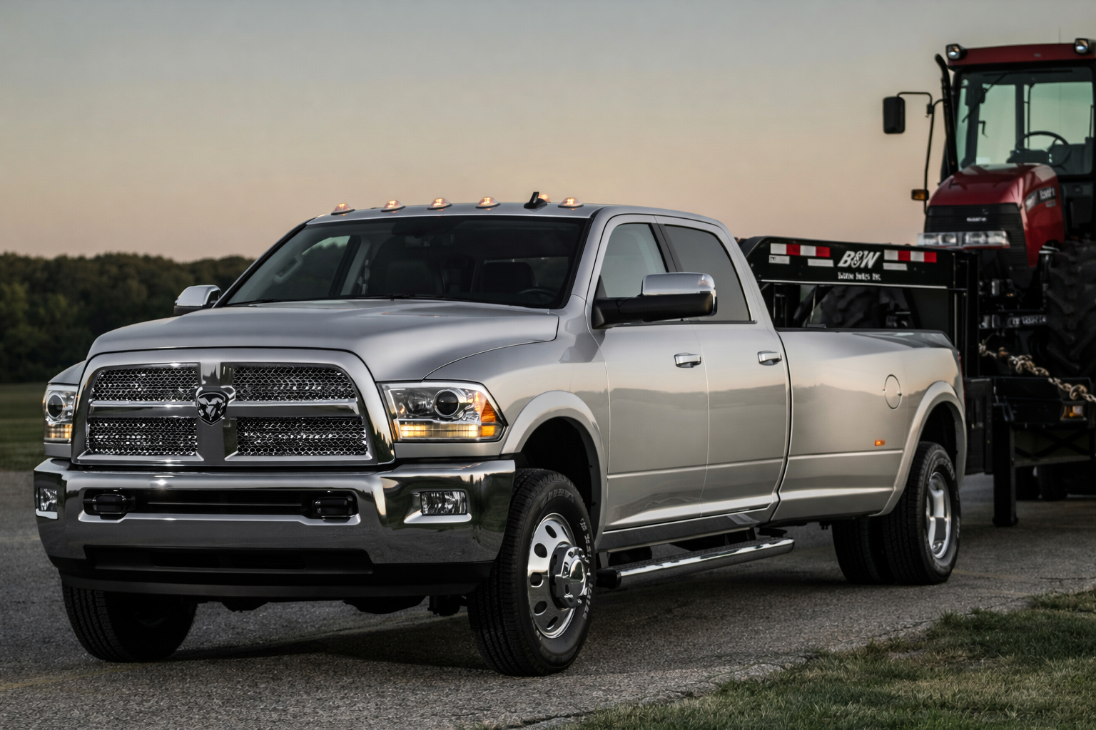 Silver Dodge Ram pickup truck pulling a red tractor on a trailer