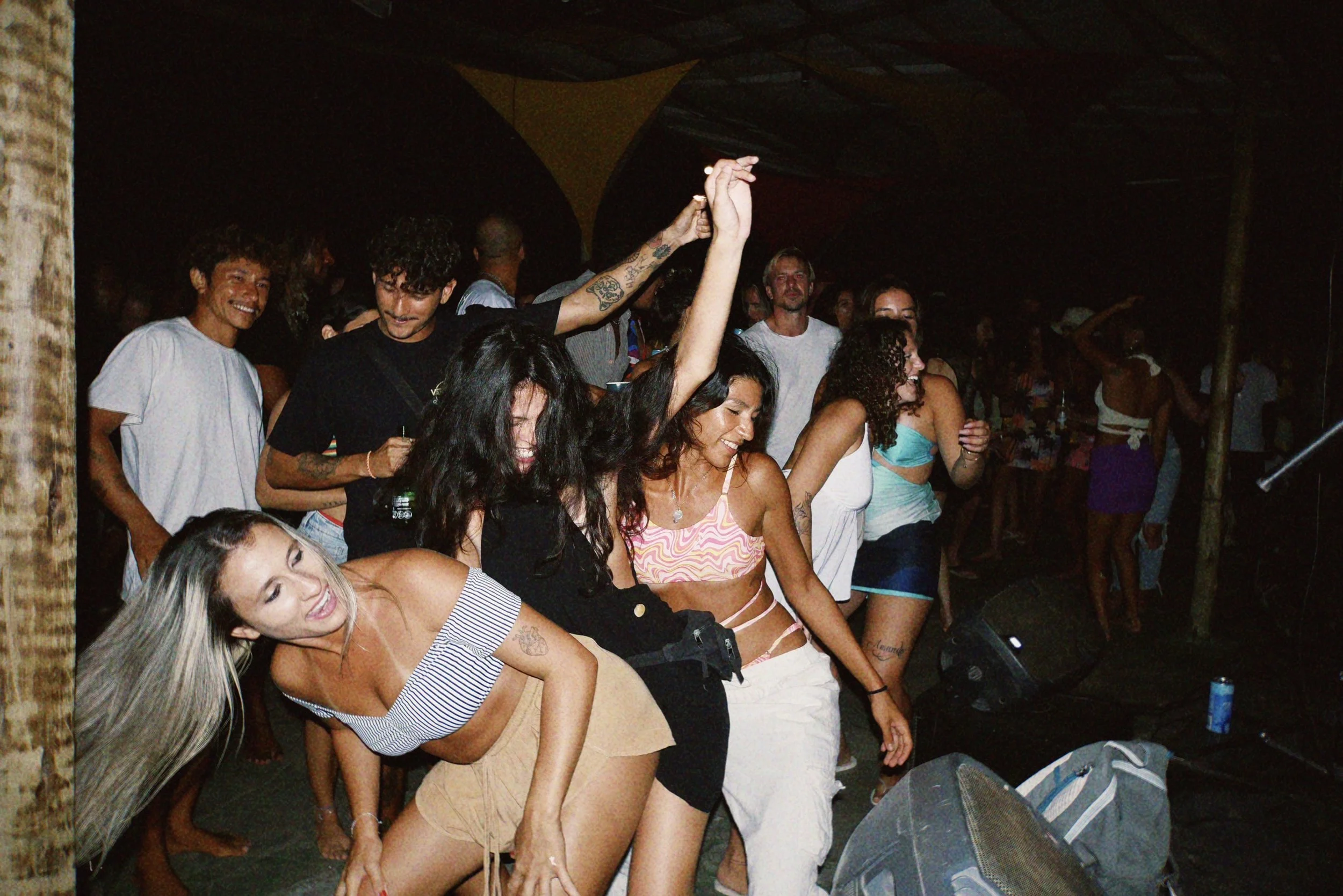 Menschen tanzen auf einer Party, lachen und haben Spaß, mit dunklem Hintergrund und Gedränge.