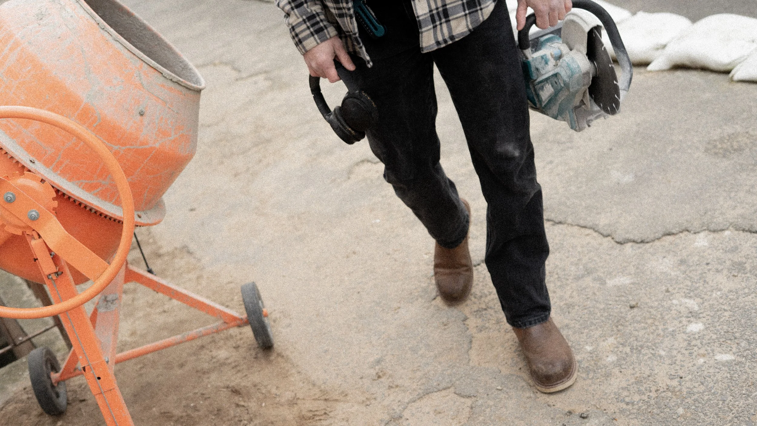 Handwerker mit Schutzbrille und Schutzhelm, mittelgroßer Baukolben auf einer Baustelle.