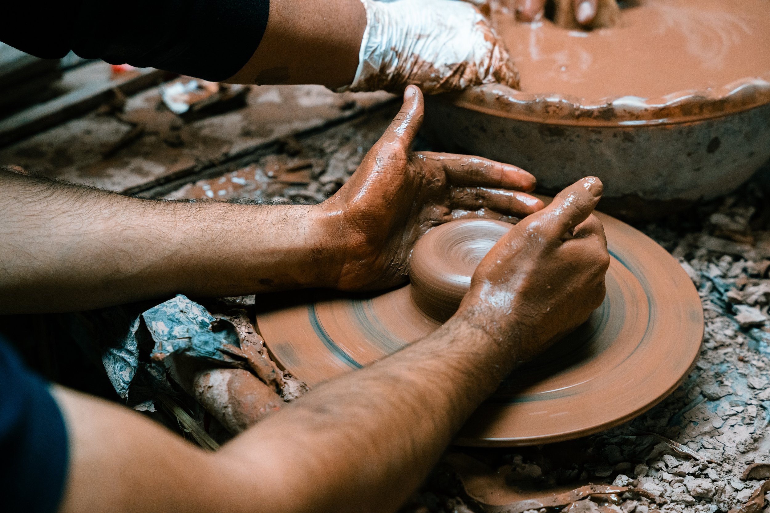 A person shaping pottery on a spinning wheel in a pottery studio.