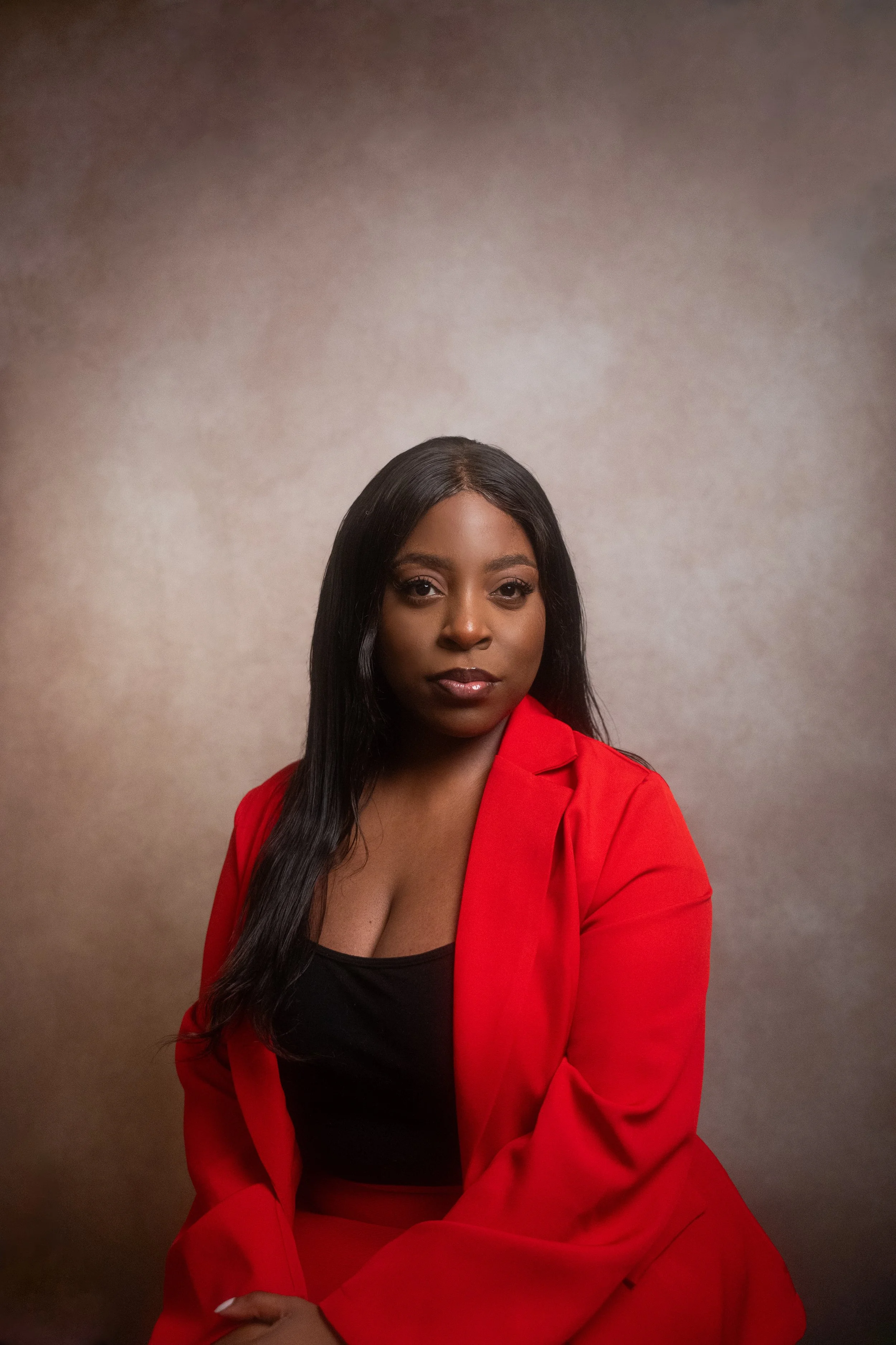 Founder Ray Sang with long black hair, wearing a red blazer over a black top, sitting against a neutral background.