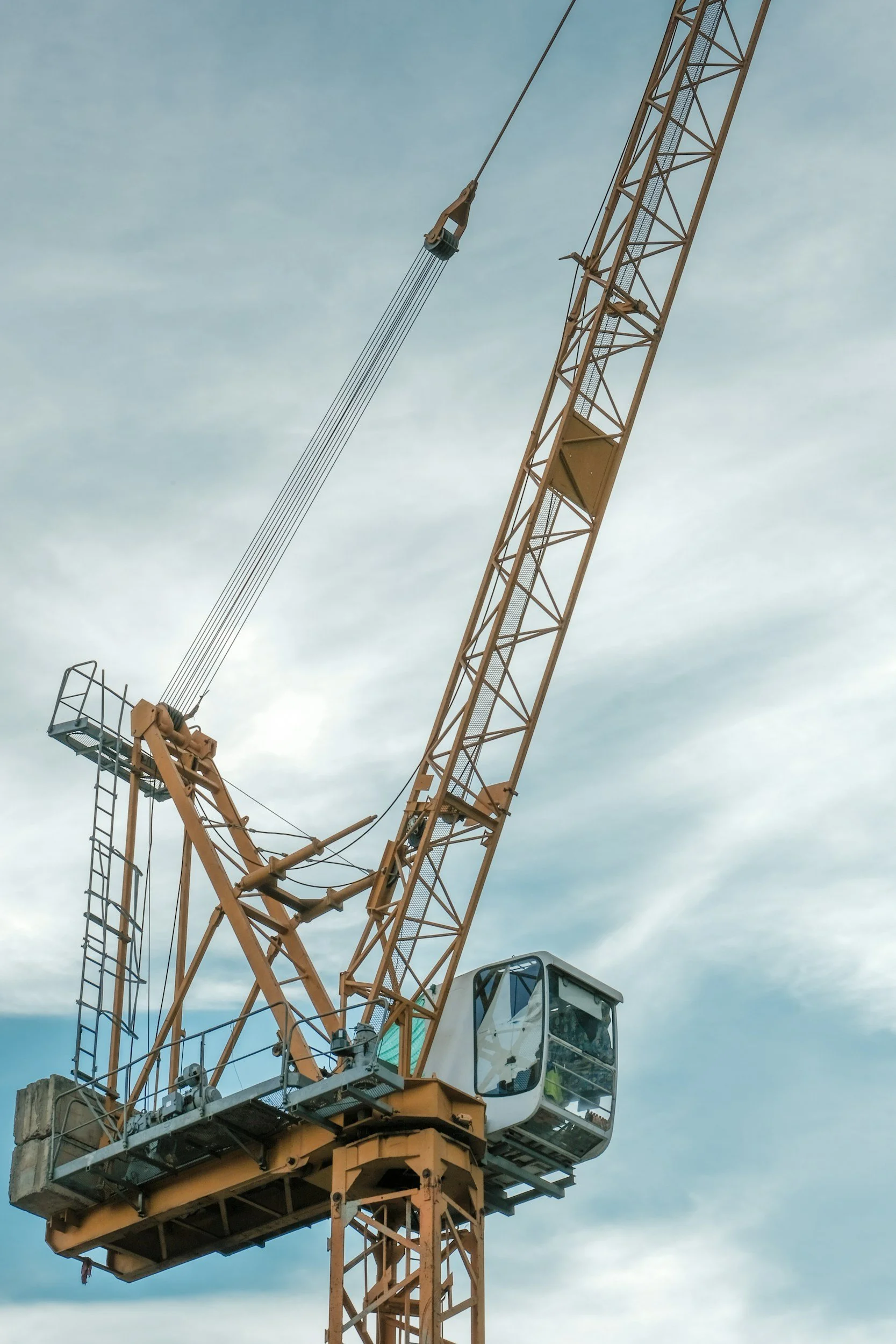 A construction tower crane against a partly cloudy sky.