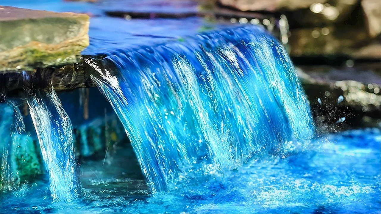 Close-up of a small waterfall with blue-tinted water flowing over rocks.