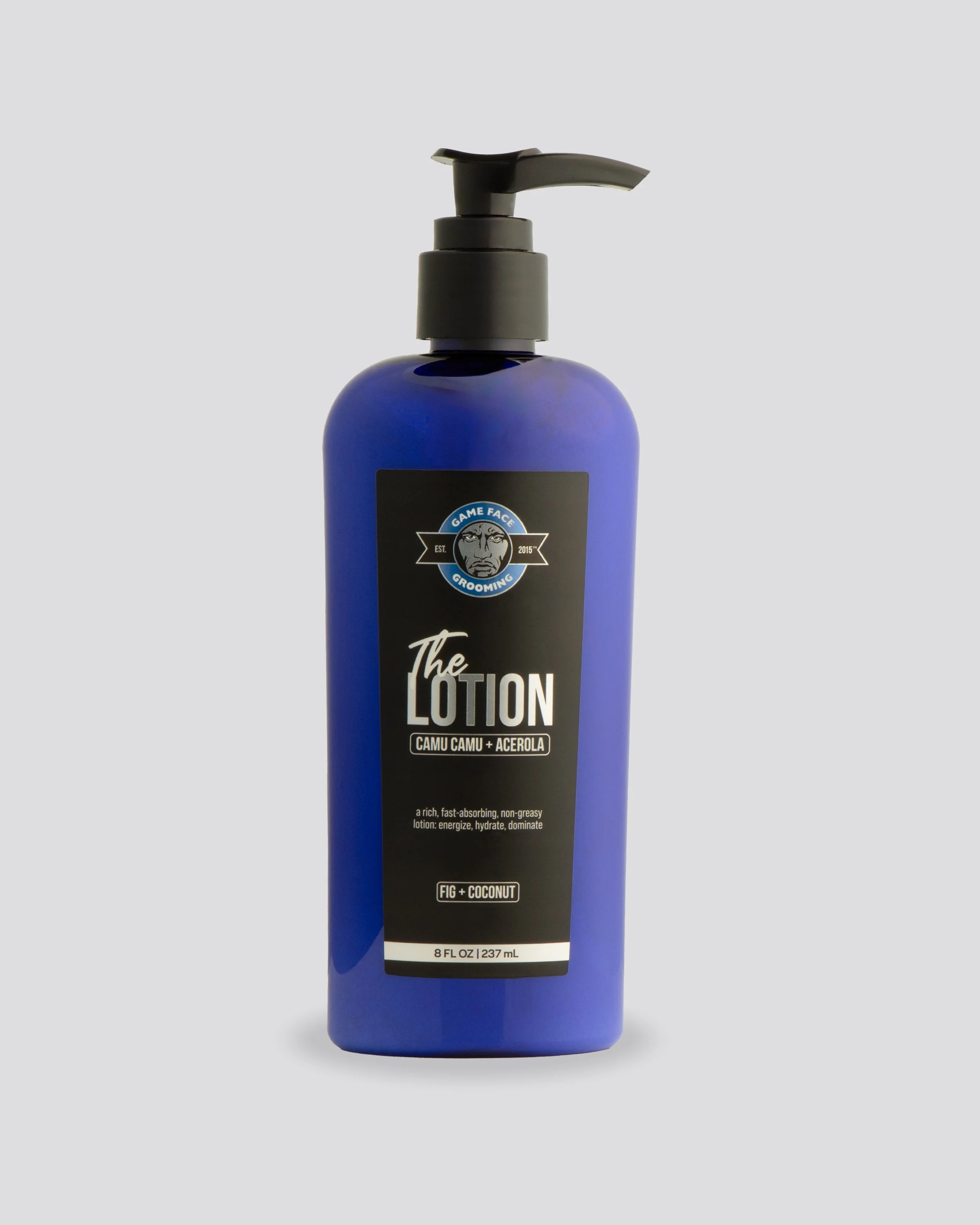 A blue bottle of grooming lotion with a black pump dispenser, labeled "The Lotion" with scent "Fig + Coconut" and a logo reading "Game Face Grooming."