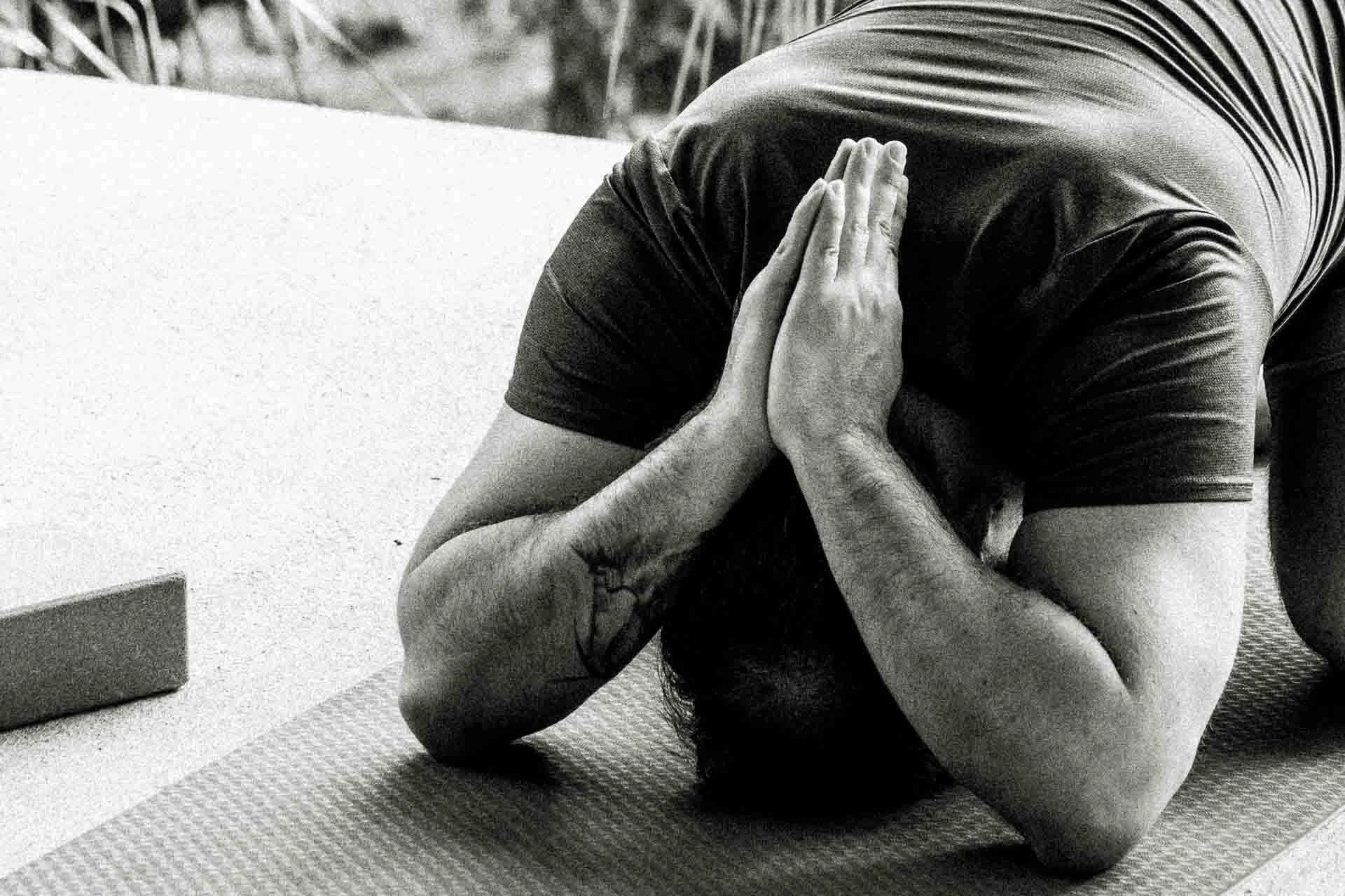 Person in a yoga pose with hands pressed together and head touching the ground on a yoga mat.