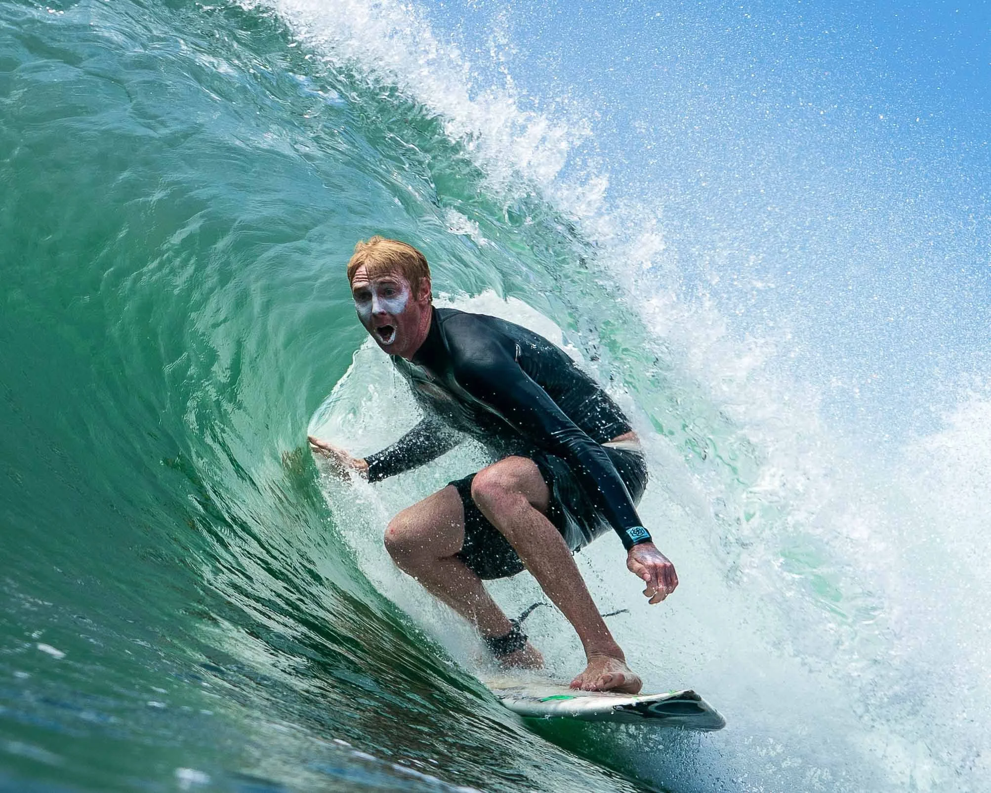 A man with painted face surfing inside a barreling wave.