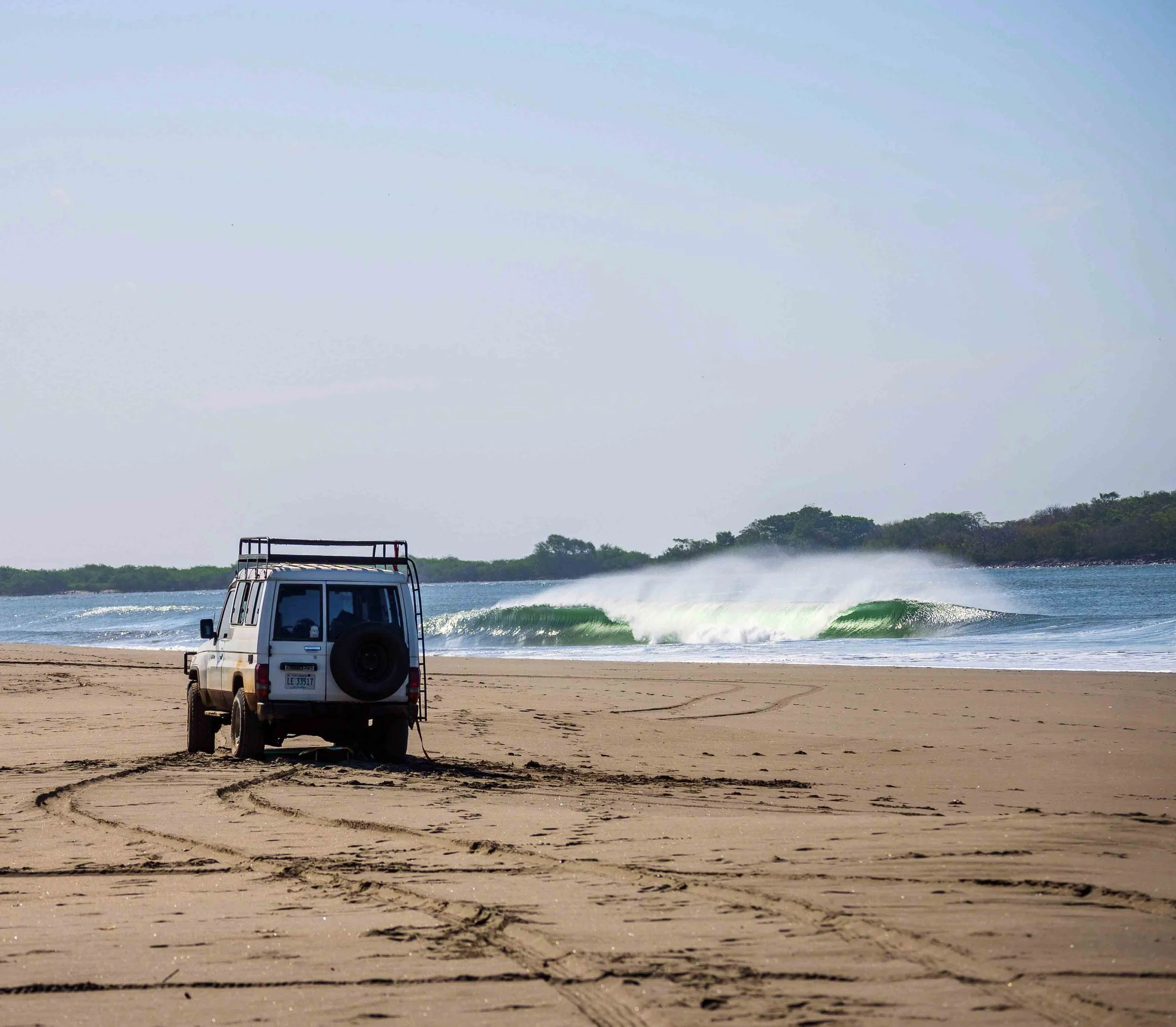 A surfer riding a wave in the ocean with three people on a boat watching in the foreground.