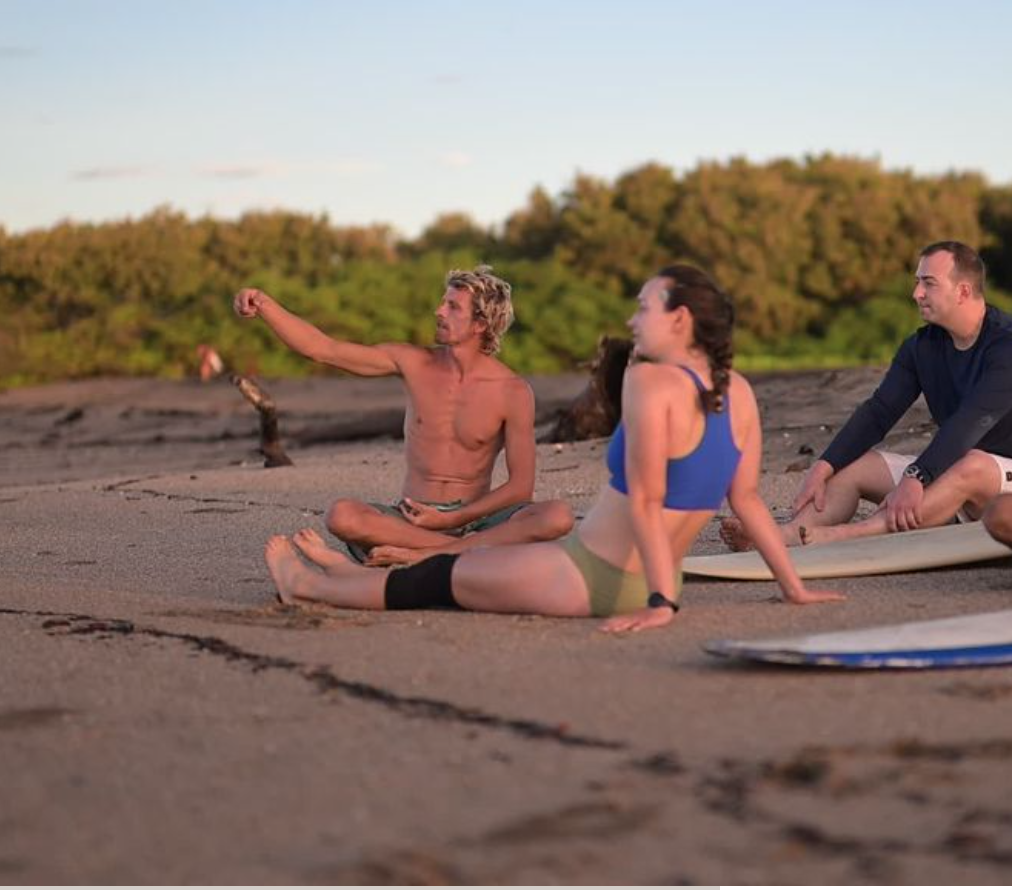 Laptop on a desk showing a surfer riding a wave at the beach with a person in curly hair in the foreground.
