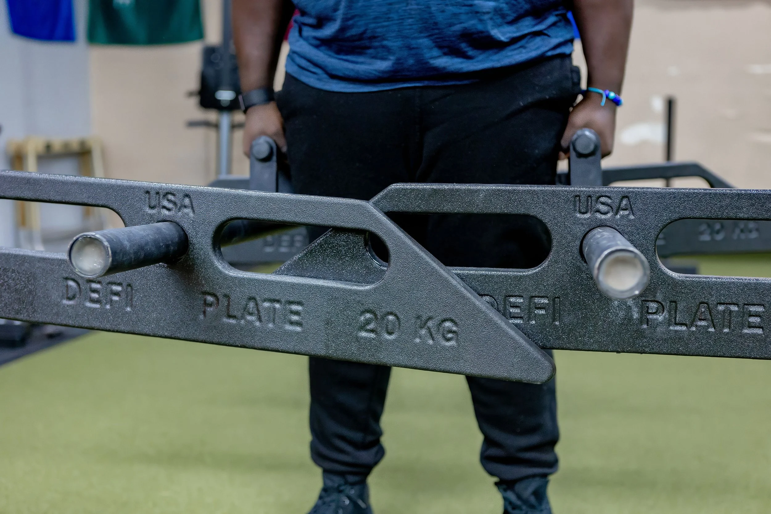 Person doing a strongman farmer carry with a spinning unique trapezoid weight plate