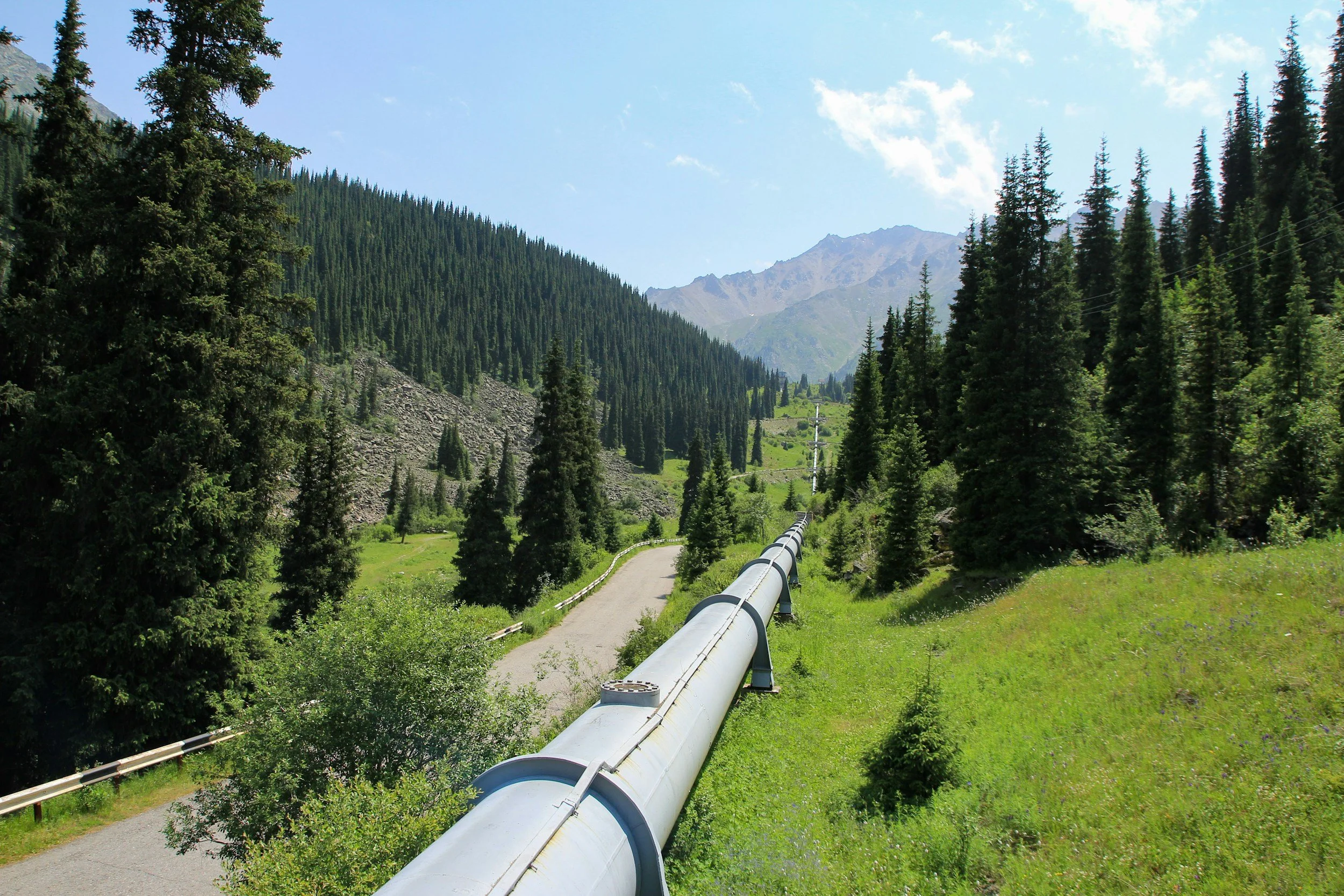 Pipeline infrastructure transporting hydrocarbons through a mountainous landscape, representing gathering, compression, treatment and storage operations.