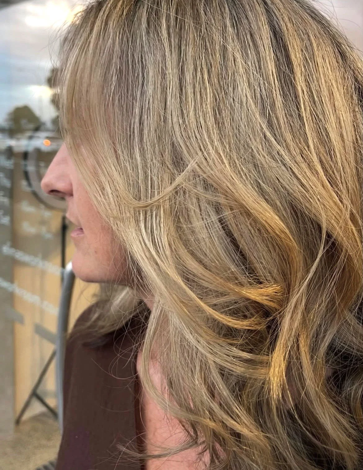 Close-up of a woman with blonde, wavy hair that is styled in loose curls.