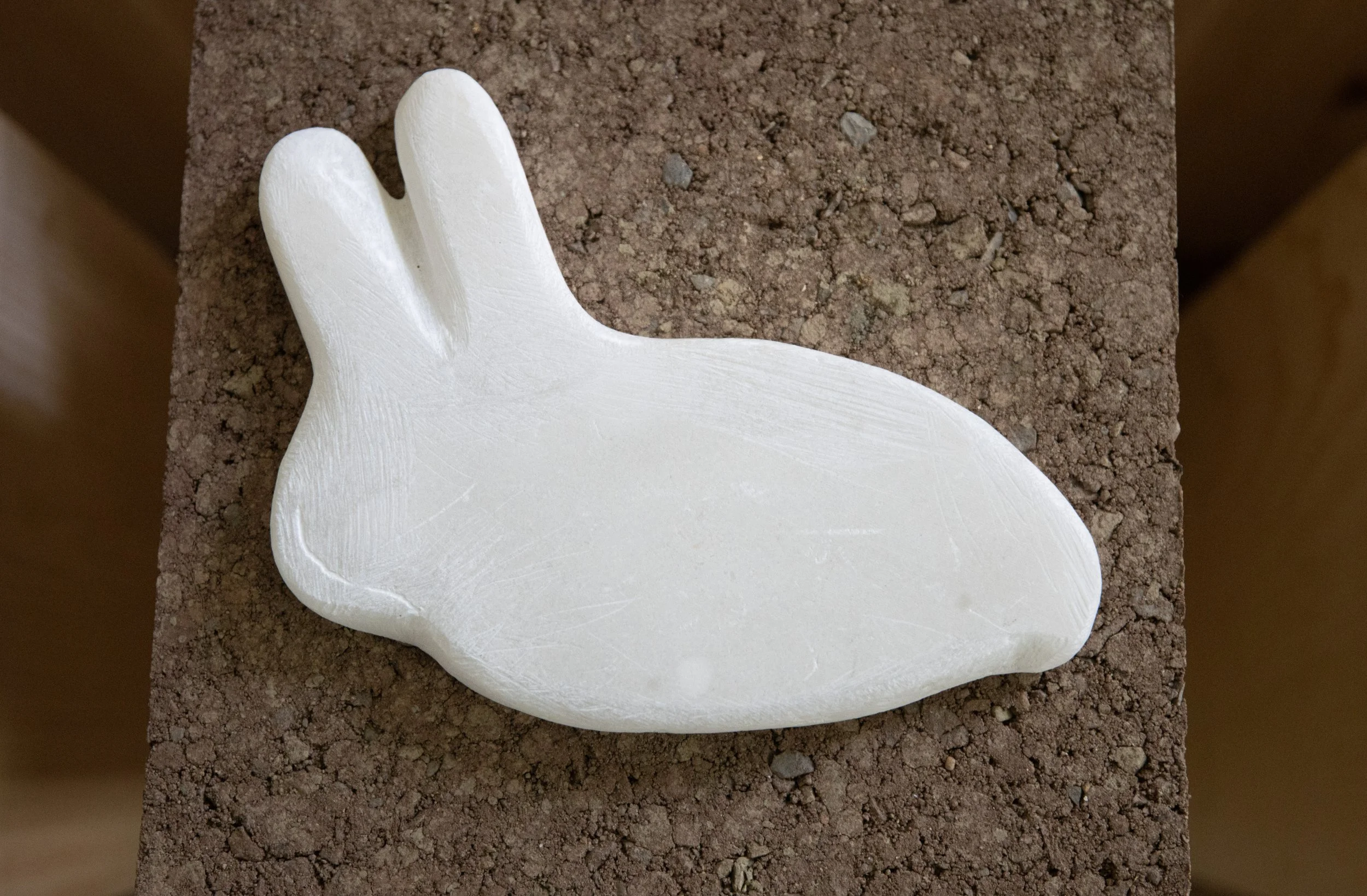 Rabbit (Whose molecule drops like a cloak without a body), 2025, alabaster, earth, pine pedestal, 31” X 11.5” X 11”, (detail)