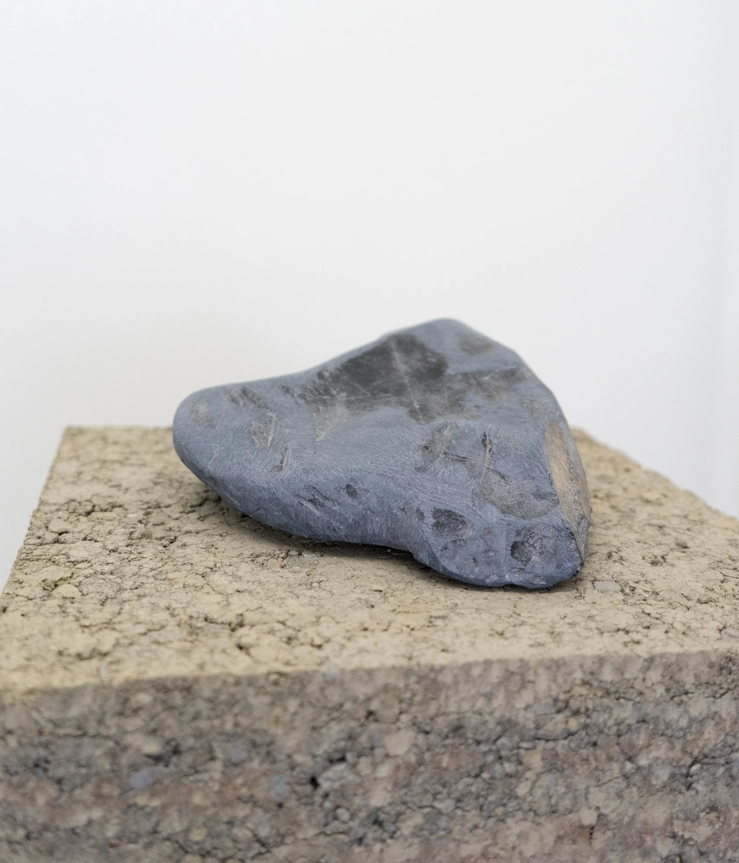 Hat (Riddle is everywhere/Because a grain shatters direction), 2025, soapstone, earth, pine pedestal, 36” X 11” X 11.5” (detail)

Photo by Henry Chapman