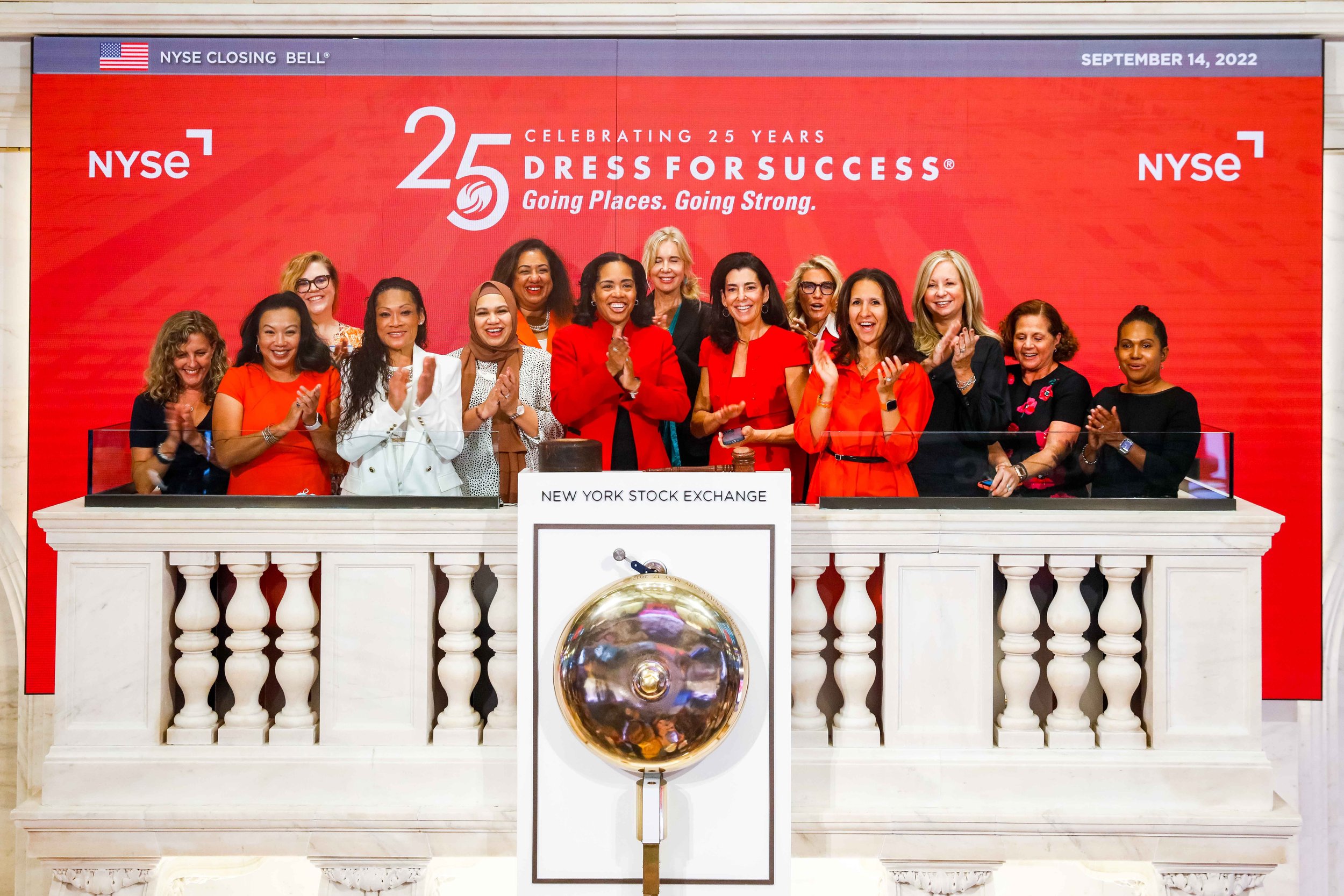 Group of women celebrating at the New York Stock Exchange during the 25th anniversary of Dress for Success on September 14, 2022, with a red background and the NYSE logo.