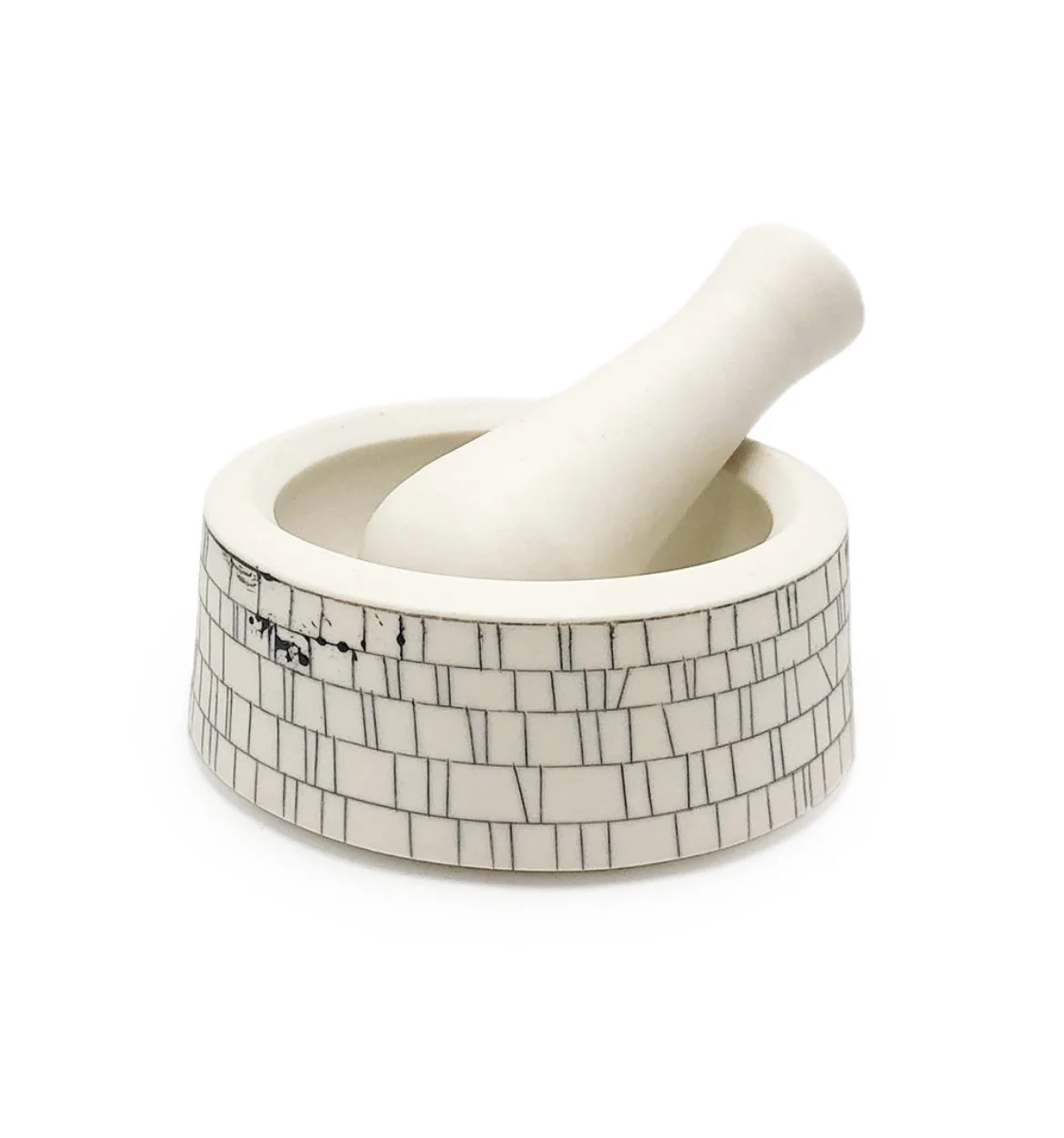 A white mortar and pestle with a brick pattern base.