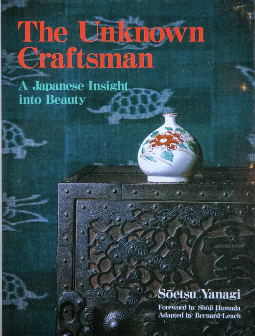 Book cover titled "The Unknown Craftsman" with a subtitle "A Japanese Insight into Beauty." The cover features a ceramic vase with orange and green floral designs placed on an intricately carved dark wooden table with a landscape of turtles in the ba