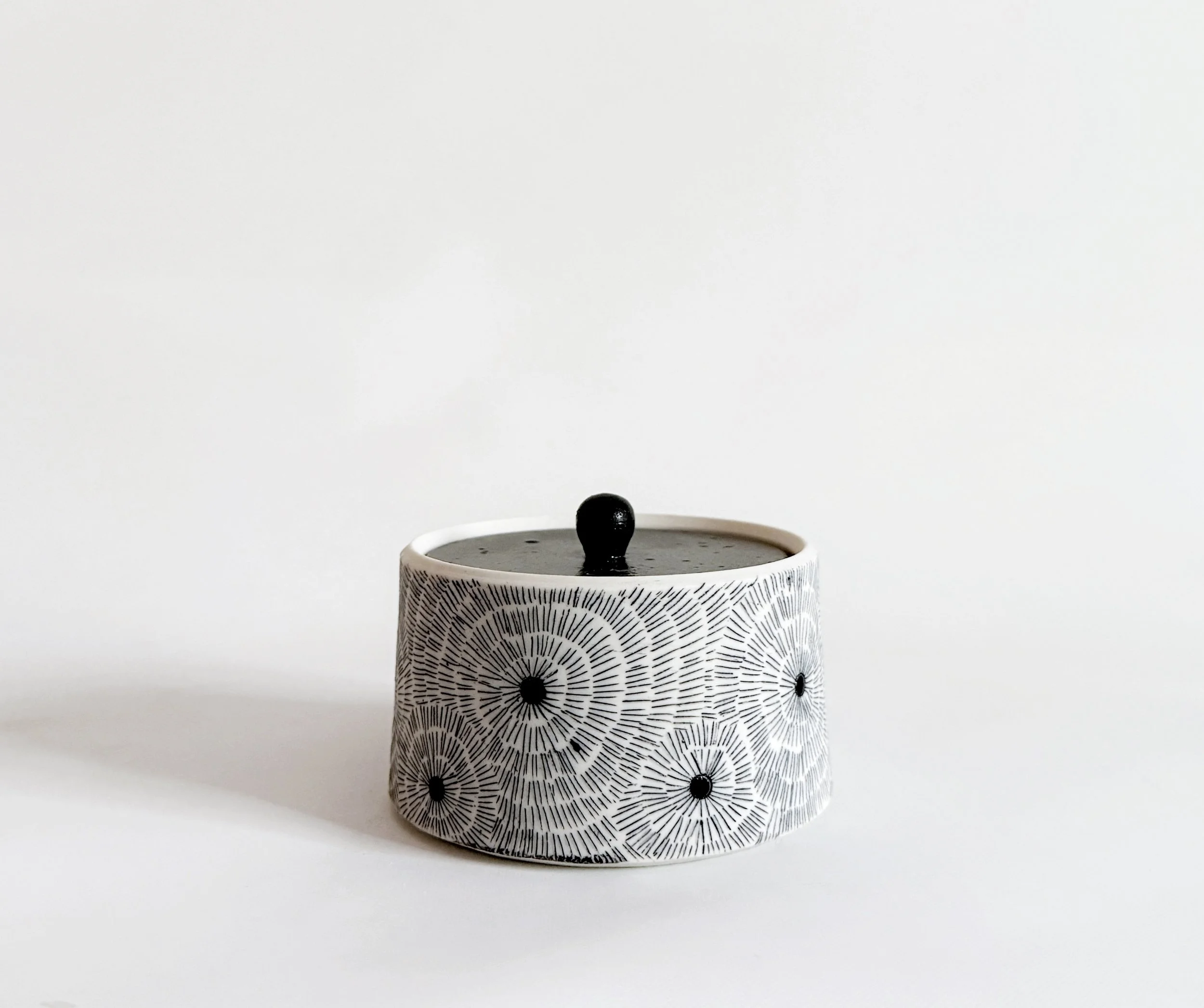 Decorative ceramic container with black and white geometric pattern, black lid with knob