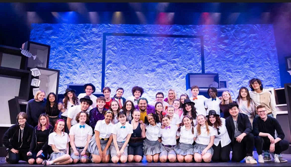 Group of young people on stage after a theater production, smiling and posing for a group photo.