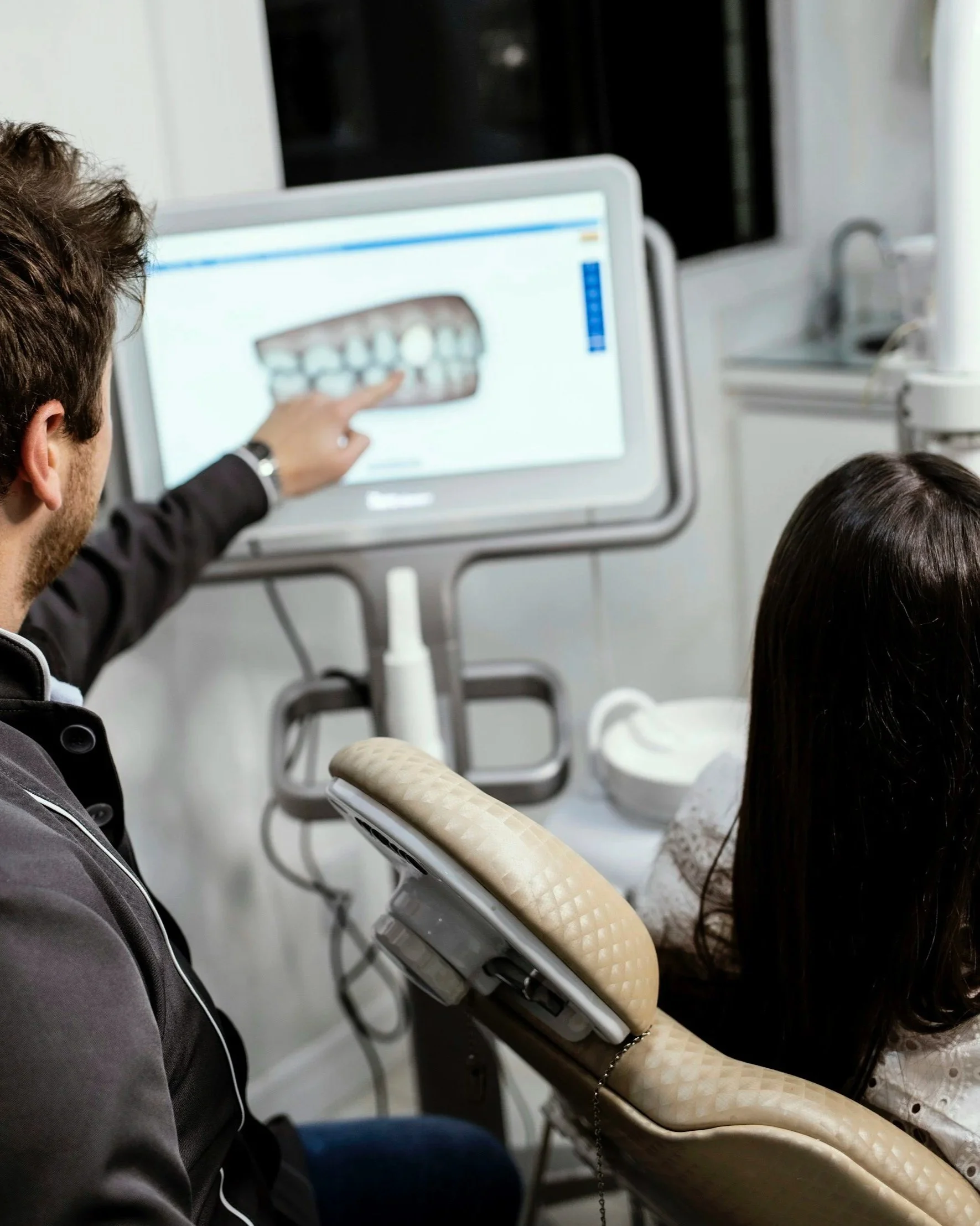 Dentist showing a digital scan of a person's teeth on a computer screen during a dental consultation.