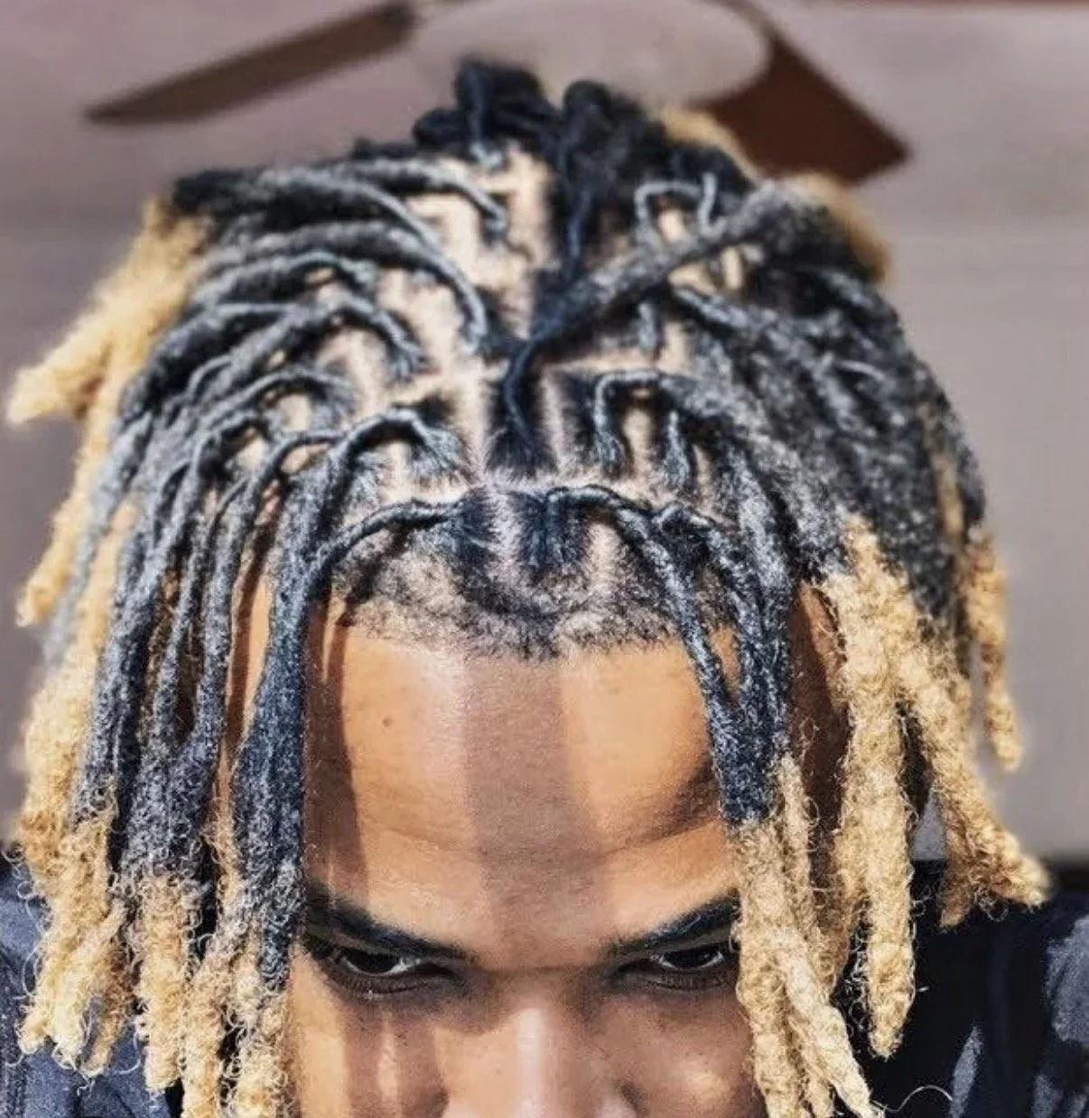 A person with dreadlocks dyed black and blonde, viewed from above.