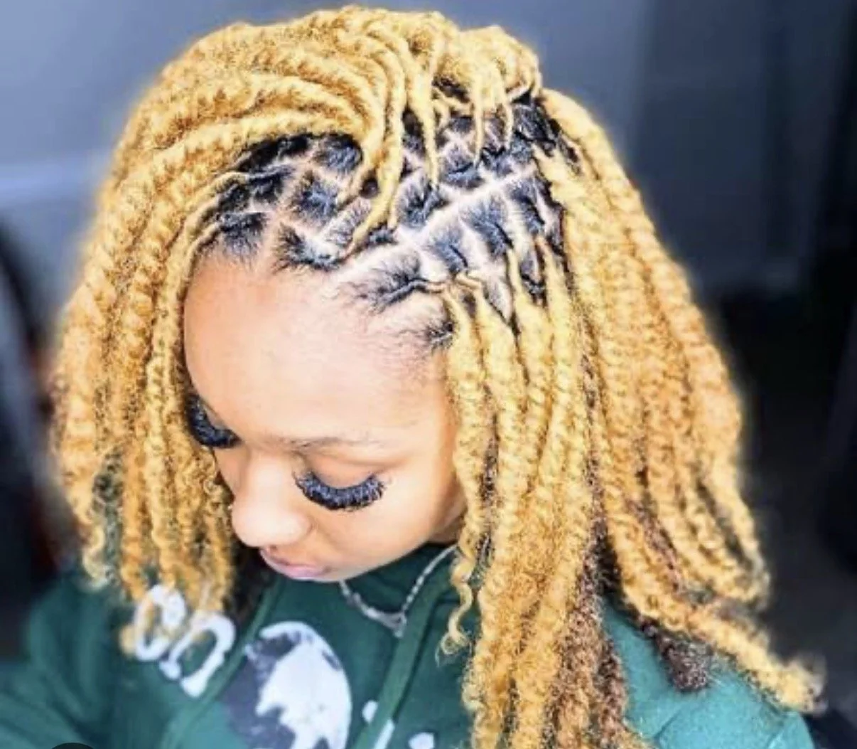 A woman with blonde dreadlocks looking down.