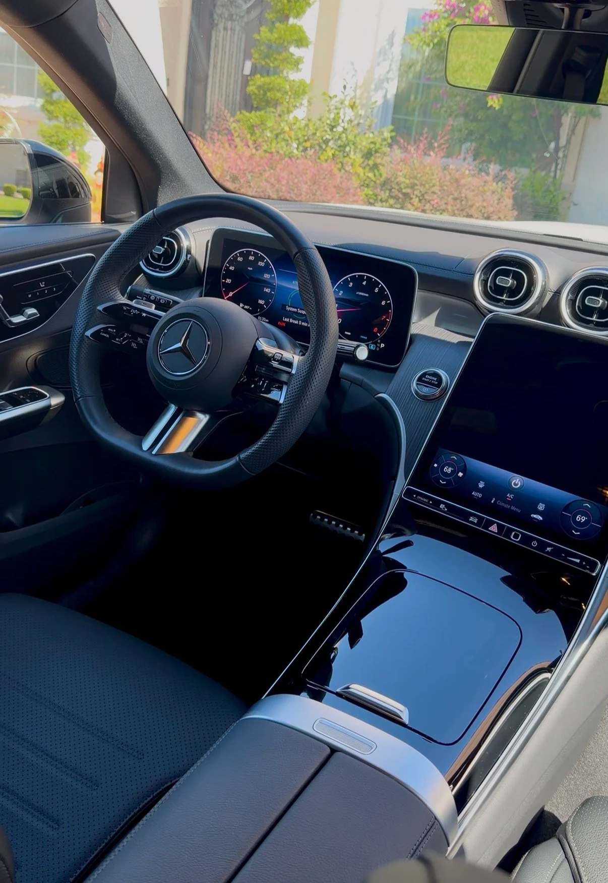 Interior of a modern Mercedes-Benz vehicle showing the steering wheel with the Mercedes logo, digital dashboard, central control screen, and air vents.