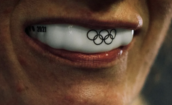 Close-up of smiling person's mouth with white Olympic-themed mouthguard displaying the Olympic rings and is marked '2021'.