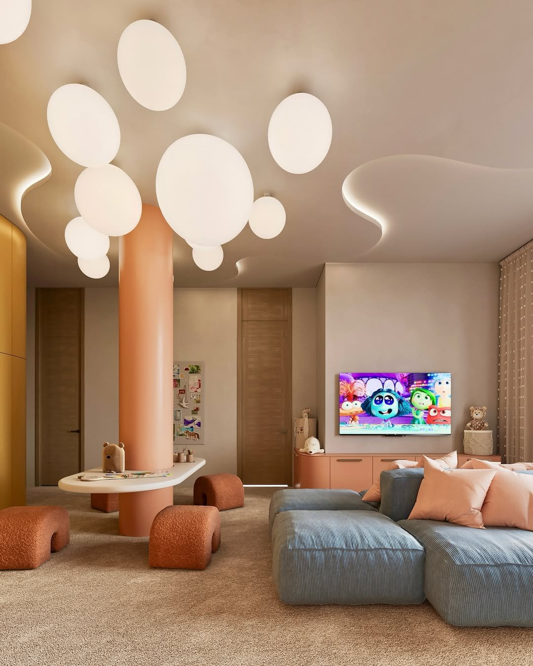 Salon moderne avec un plafond à lampes rondes suspendues, un canapé gris avec des coussins roses, une télévision affichant une émission pour enfants, et un mobilier pastel dans une décoration chaleureuse et cosy.