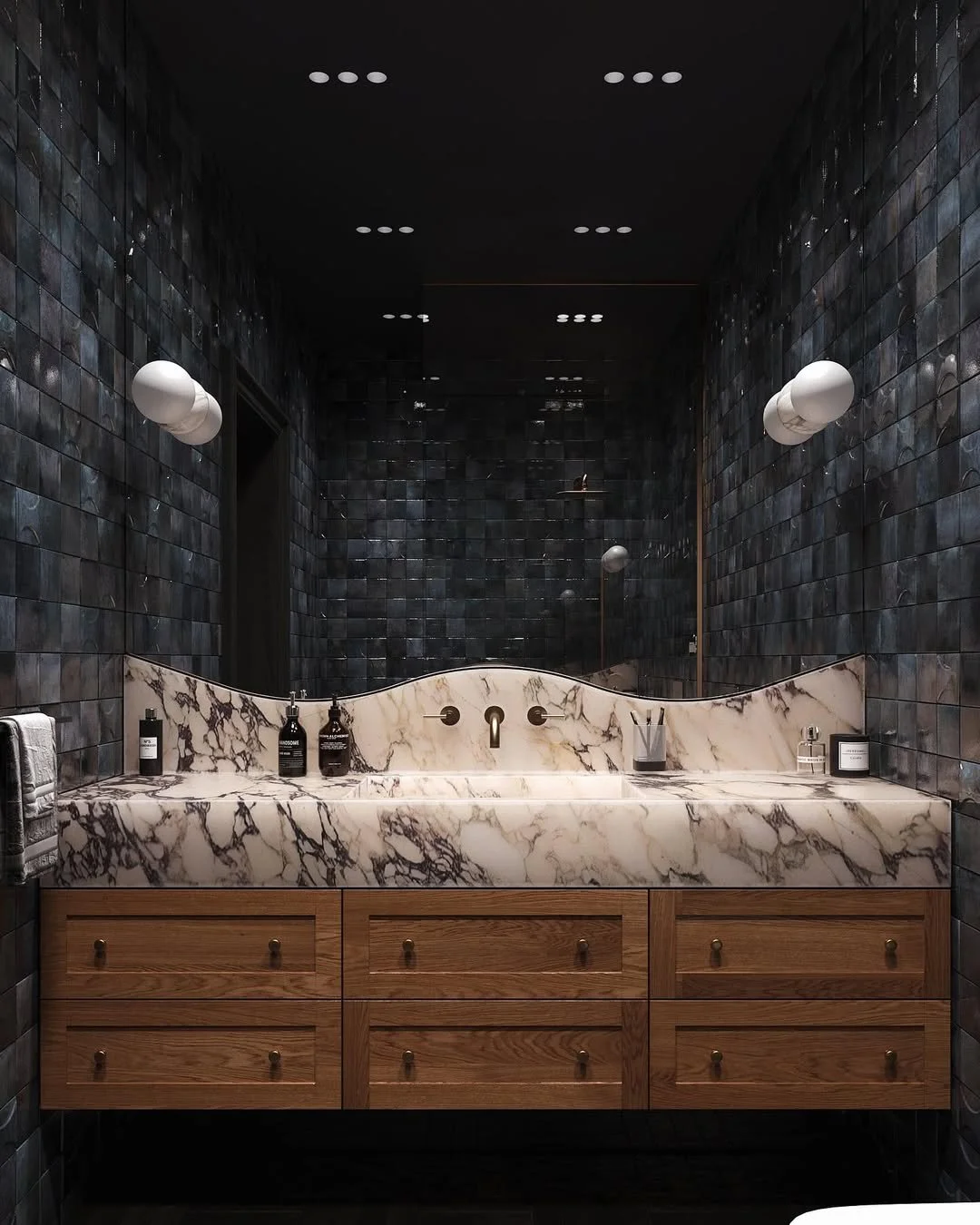 Un lavabo en marbre blanc avec des veines noires, intégré dans un meuble en bois avec tiroirs. Surroundings: murs en tuiles noires et éclairage mural blanc.