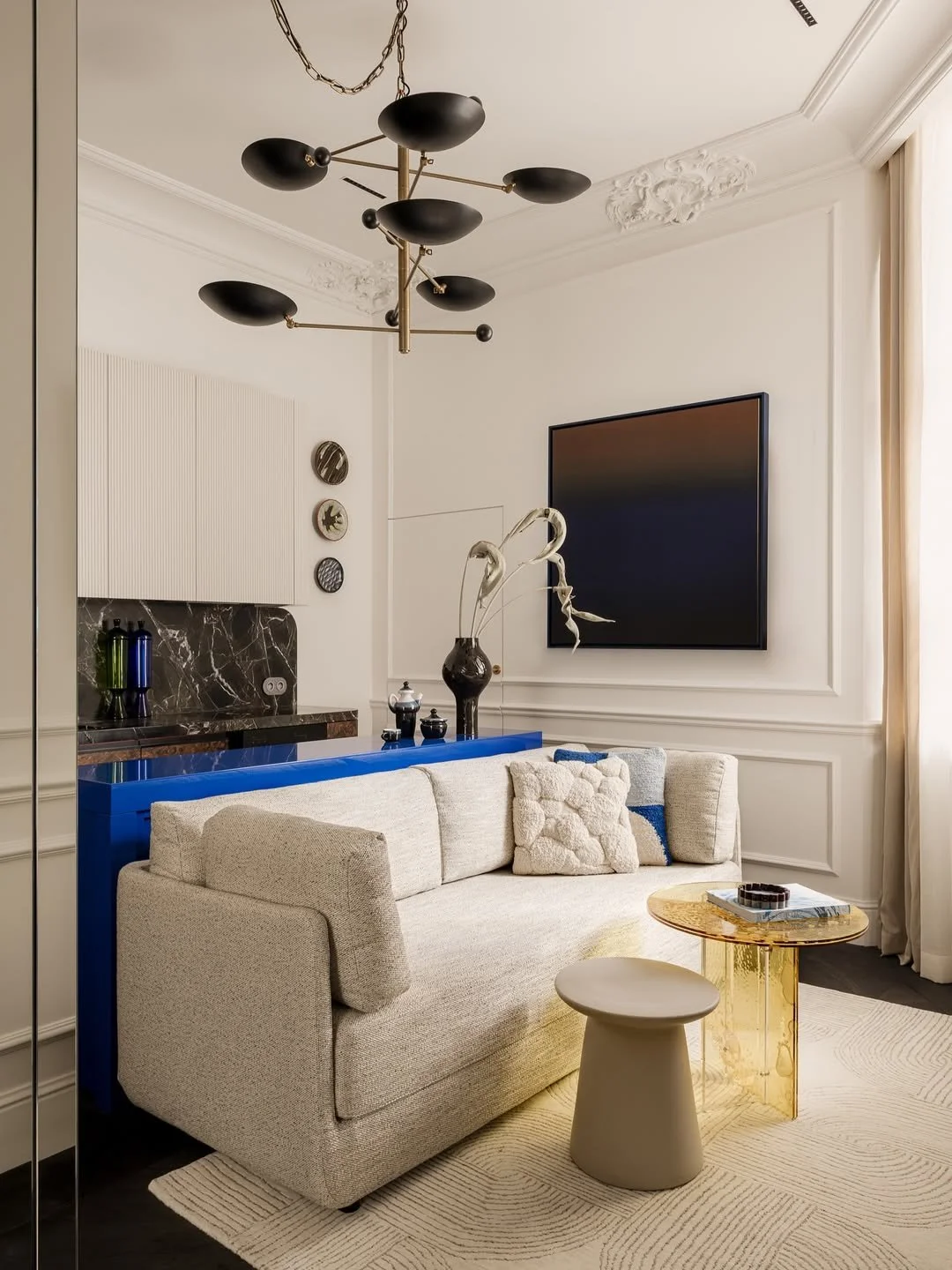 Salon moderne avec canapé beige, table en marbre doré, TV suspendue, éclairage design, décor élégant et minimaliste.