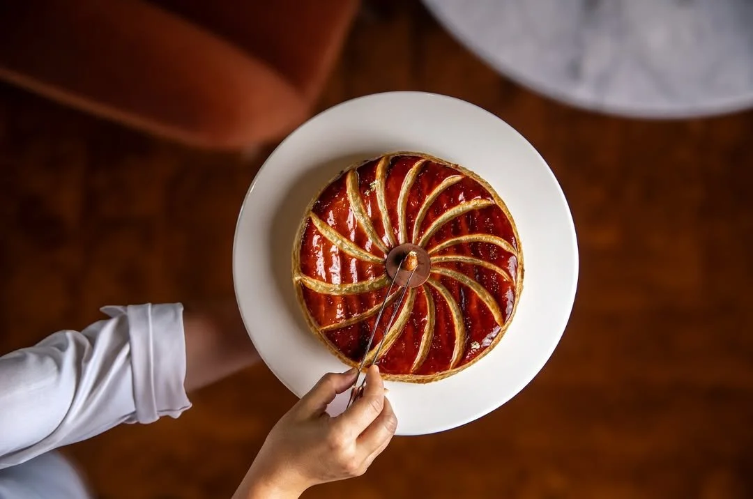 Gâteau rond avec un glaçage brillant rouge, décoré de rayures dorées en spirale.