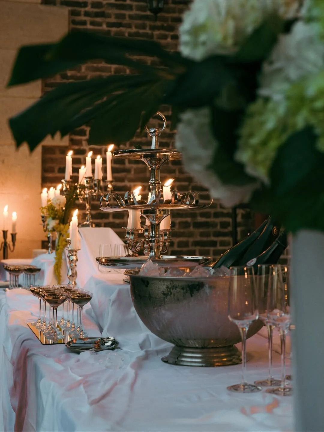 Table de réception décorée avec des chandeliers et des verres, featuring un centre de table avec des fleurs, dans une ambiance chaleureuse et élégante.