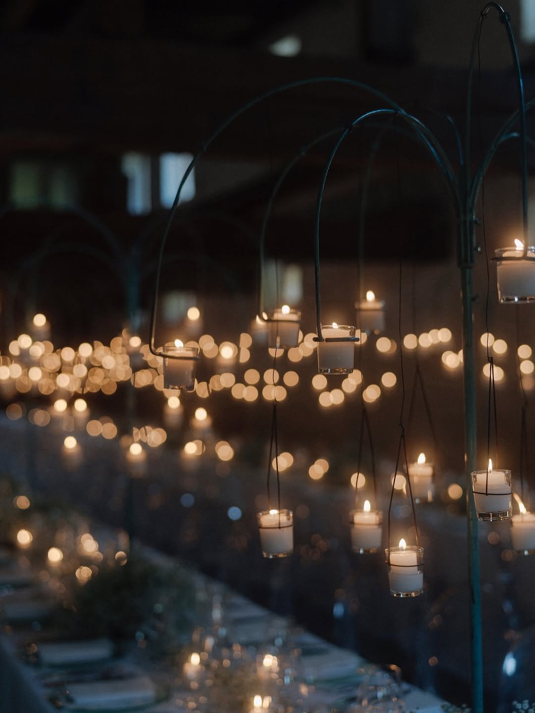 Petites bougies allumées suspendues dans un cadre sombre.