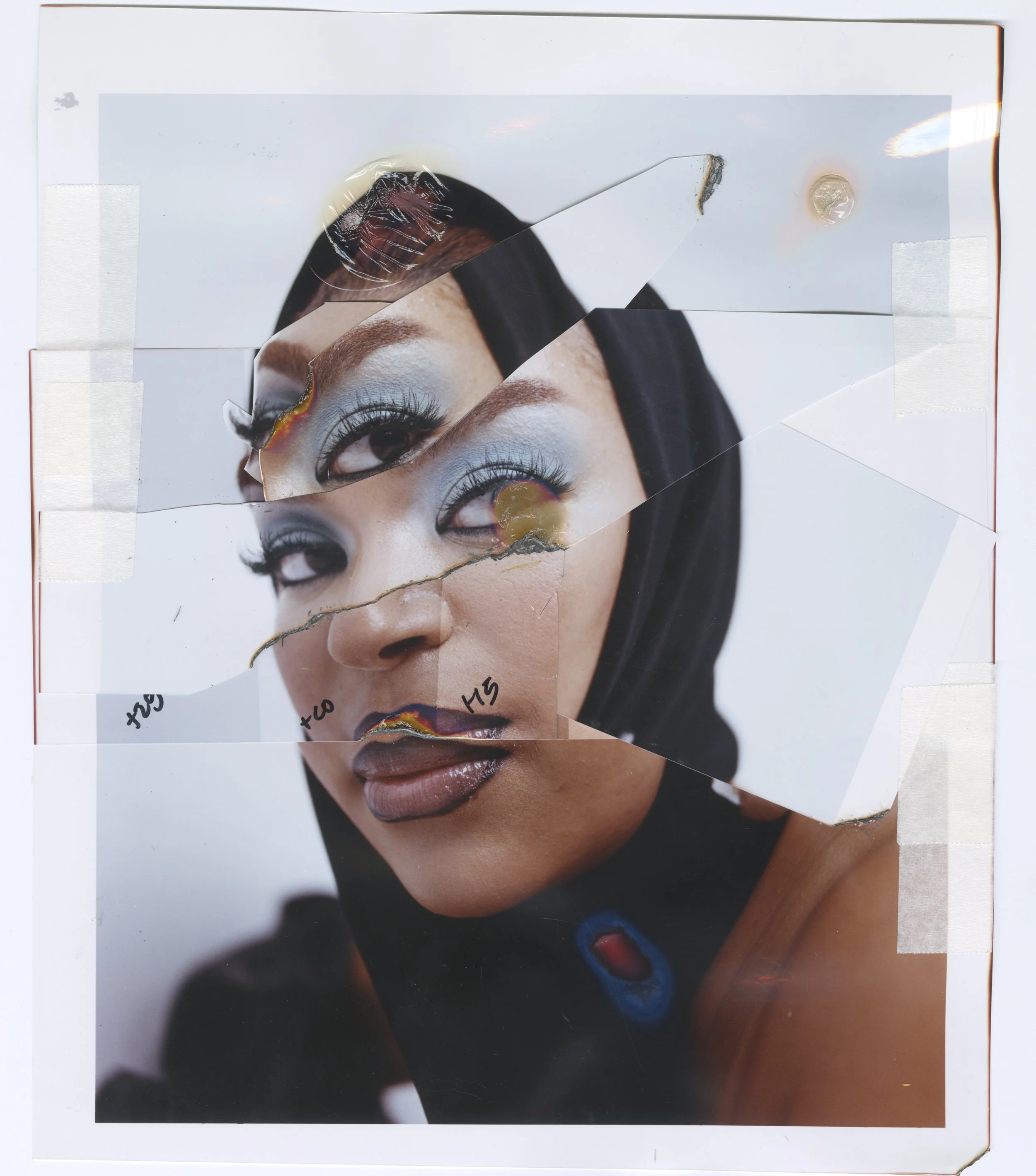 Torn photograph of a woman's face with makeup, taped onto a white background.