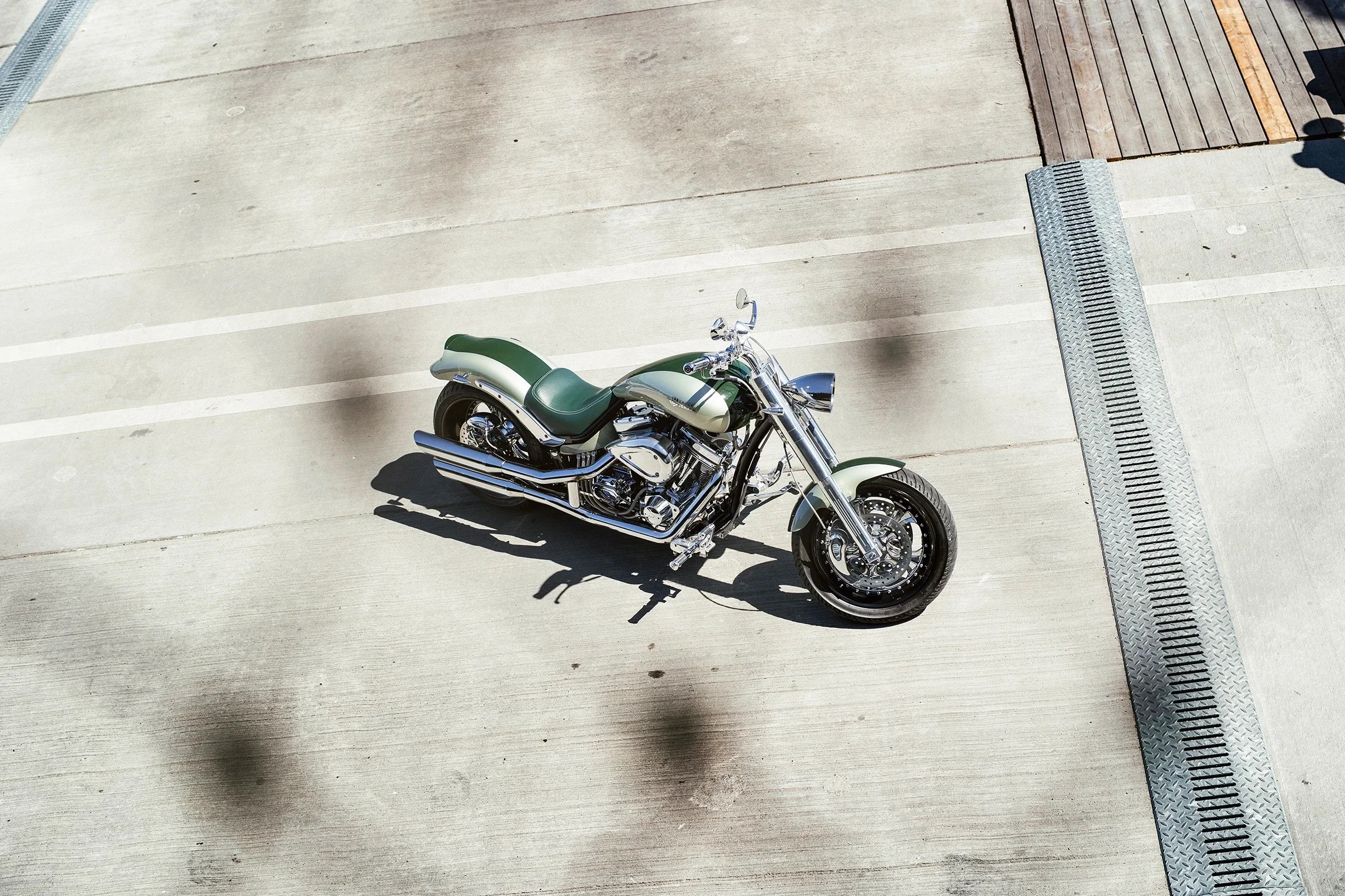 A green and chrome motorcycle parked on a concrete surface.