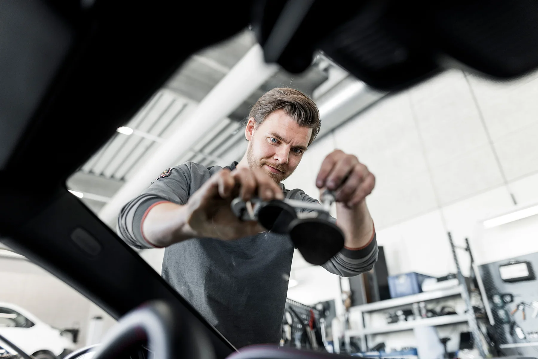 A mechanic using a tool to repair a vehicle in a garage.