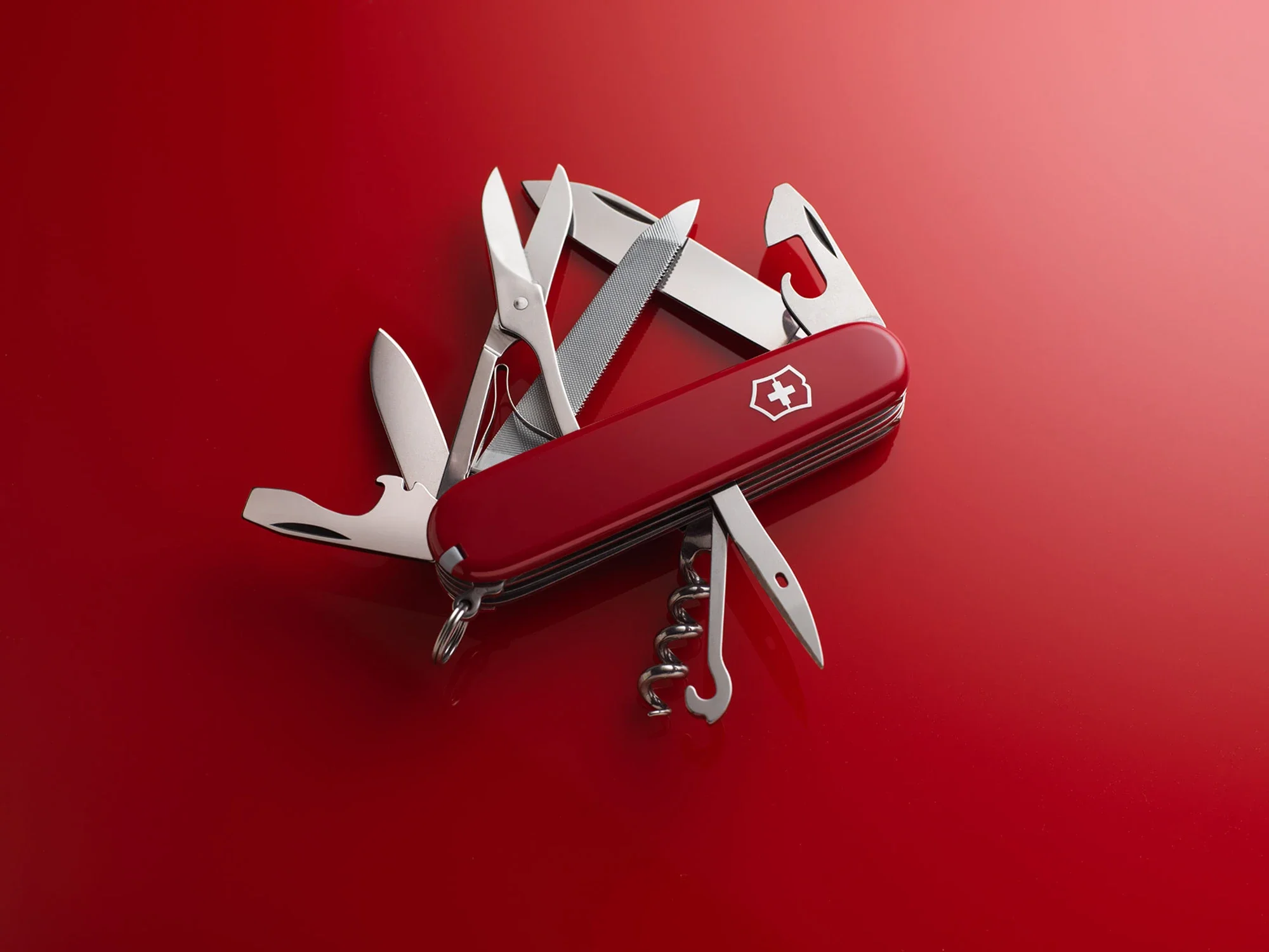 Swiss Army knife with multiple tools extended on a red surface.