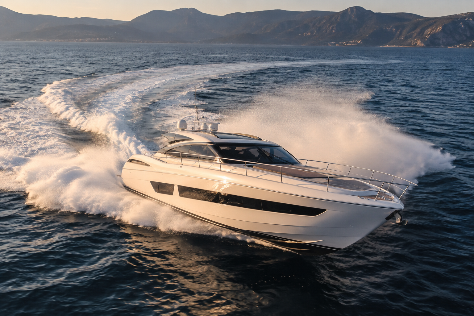 A luxury white yacht cruising on the ocean, leaving a trail of white foam behind with mountains in the background at sunset