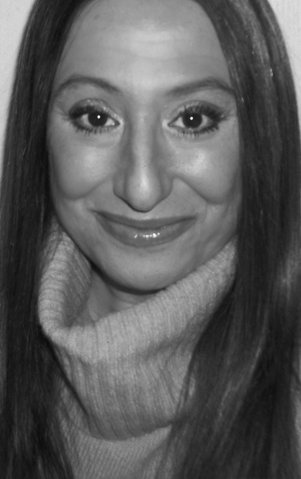 Black and white photo of a woman with long dark hair, smiling, wearing a turtleneck sweater.