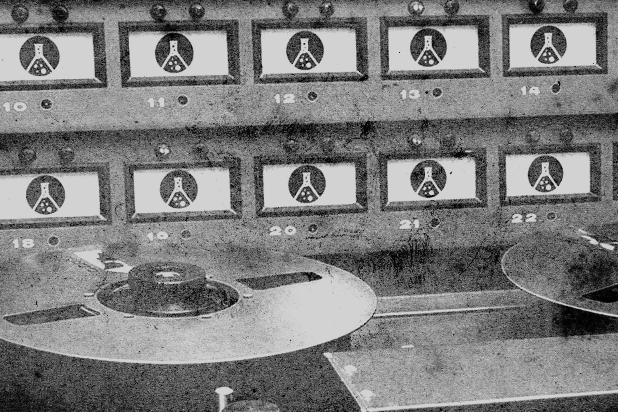 Black and white image of a vintage board game with numbered compartments and a game piece on the board.