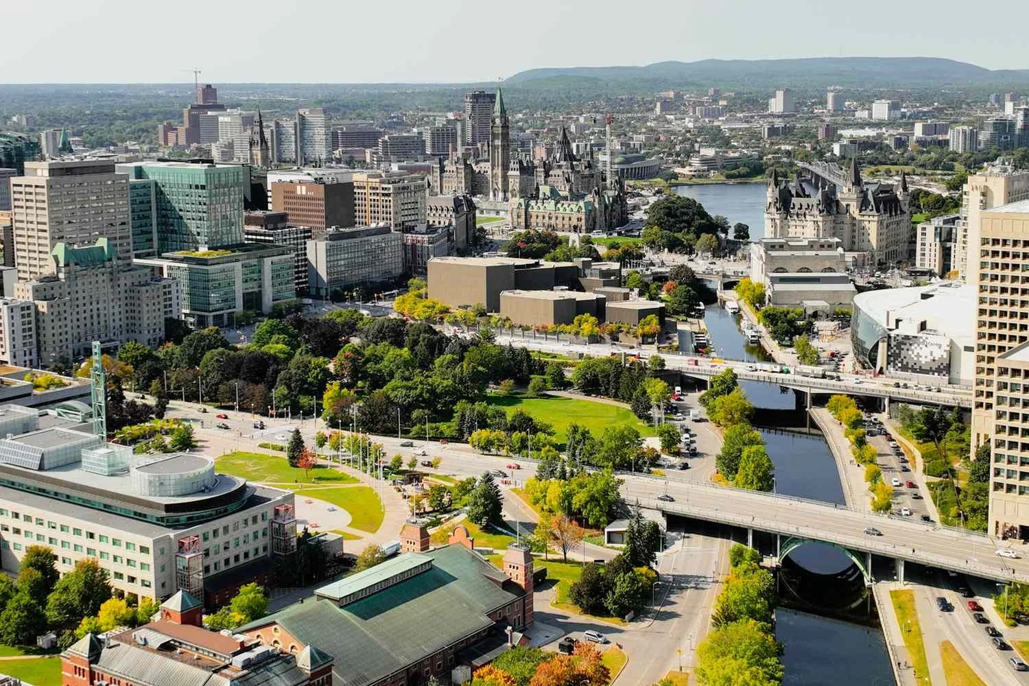 Aerial view of a cityscape with skyscrapers, bridges, a river, and green parks.