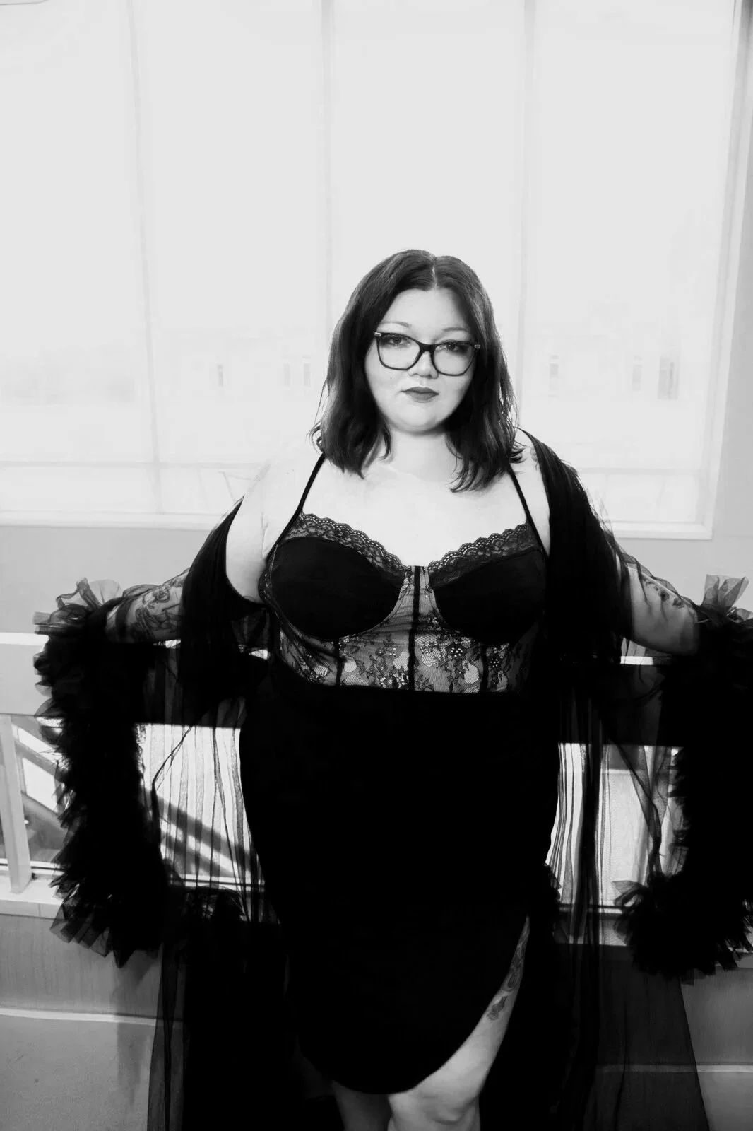 black and white photo of a beautiful woman with glasses on in a hotel lobby