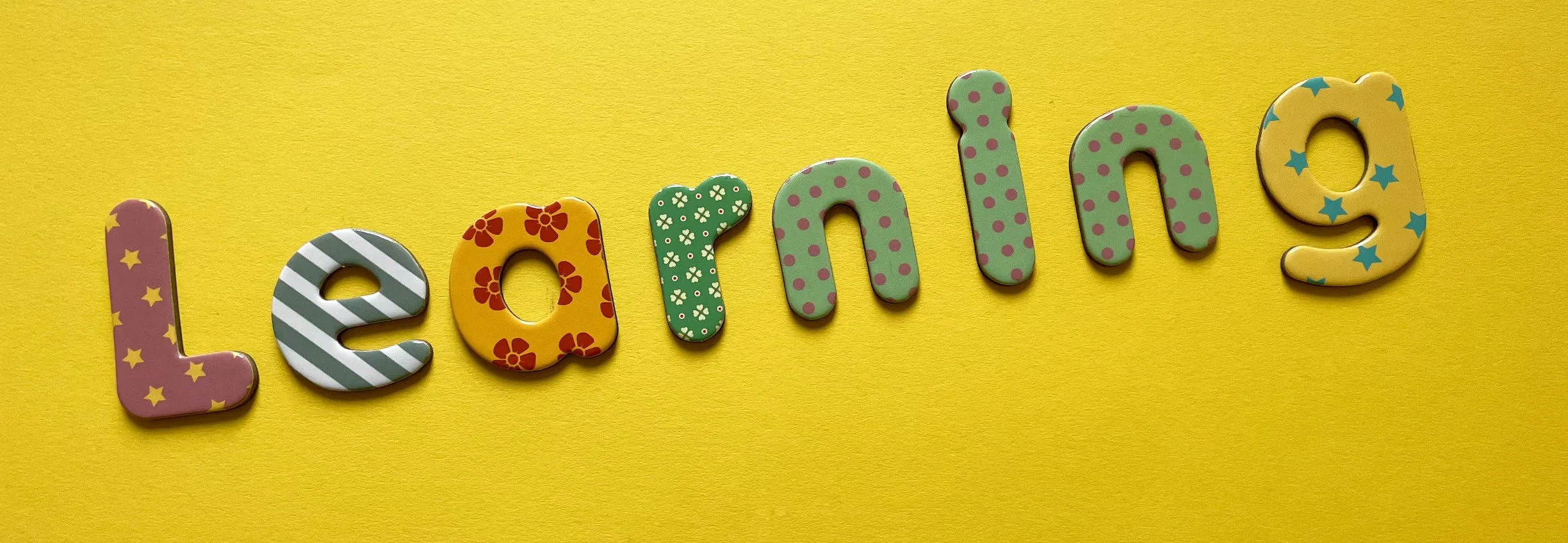 Colorful decorative letters spelling 'Learning' arranged on a yellow background.