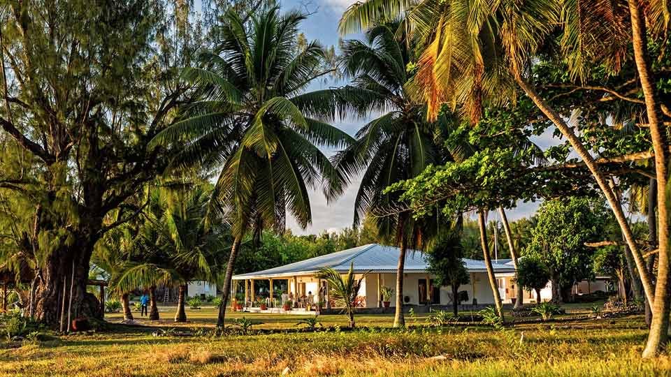 The new Farquhar Atoll Lodge in Seychelles, surrounded by green palm trees and lush tropical vegetation.