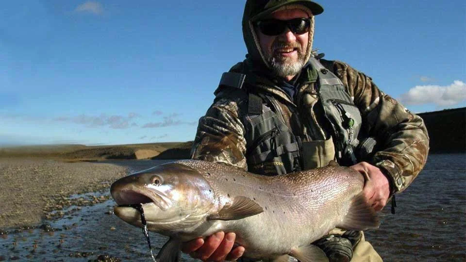 Angler holding a huge rainbow trout caught on the Barrancoso River, a tributary of Jurassic Lake in Argentina, where Estancia Laguna Verde Lodge has exclusive fishing rights.