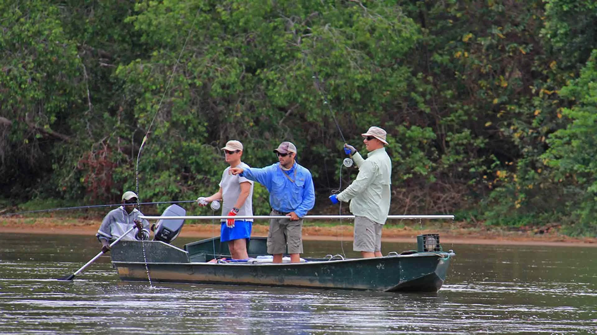 Four anglers fly fishing for Tigerfish from a boat on a jungle river in Tanzania, Africa.