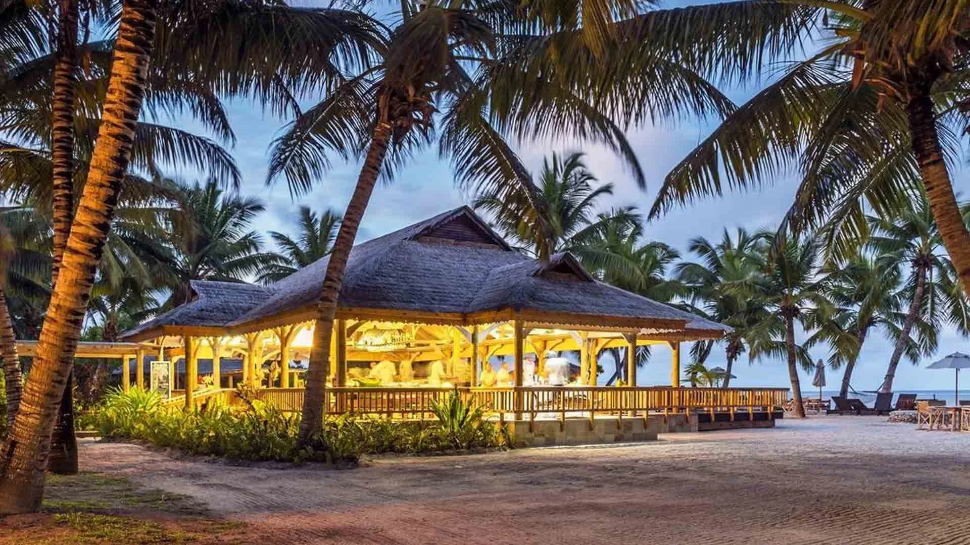 alphonse island lodge outdoor restaurant lit at night surrounded by palm trees on sandy beach