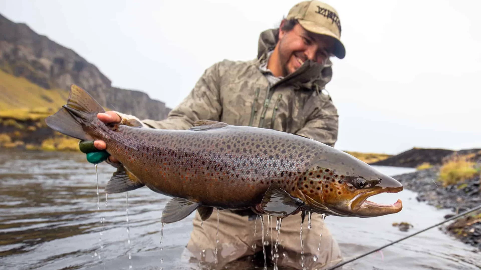 Smiling angler at Battle Hill Lodge holding a large sea trout caught fly fishing in Iceland.