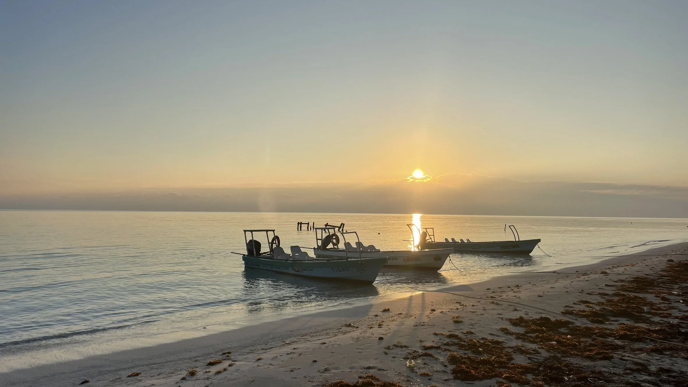 Fly fishing boat moored on the beach at sunrise in front of Kay Fly Lodge on Ascension Bay in Punta Allen, Mexico.