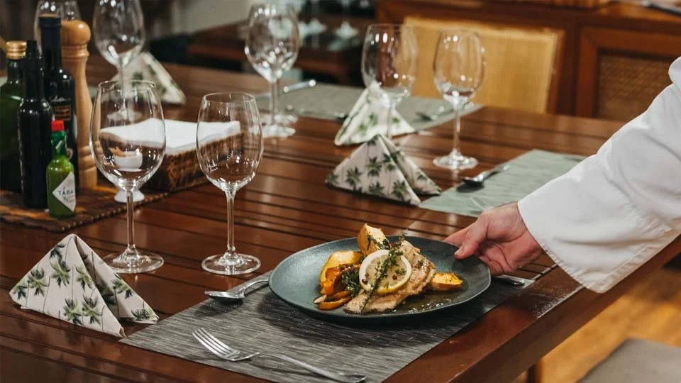 Dinner plate with fine cuisine and wine glasses served on the Untamed Amazon liveaboard,
